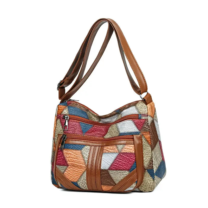 Women's crossbody bag with colorful geometric patchwork and brown leather trim, front zip pocket
