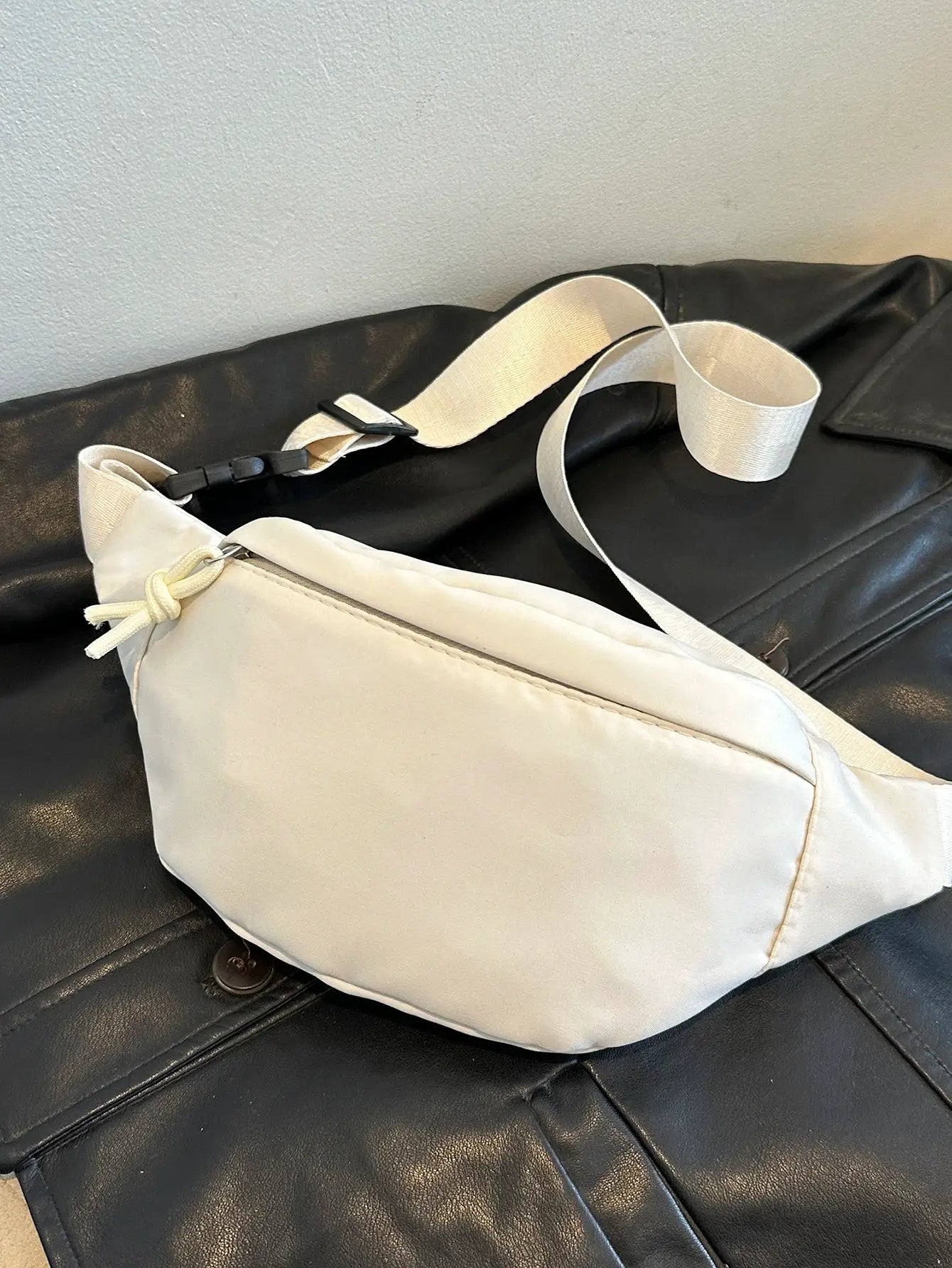Fanny pack waist bag in cream with adjustable beige strap and black buckle; crossbody travel-ready style.