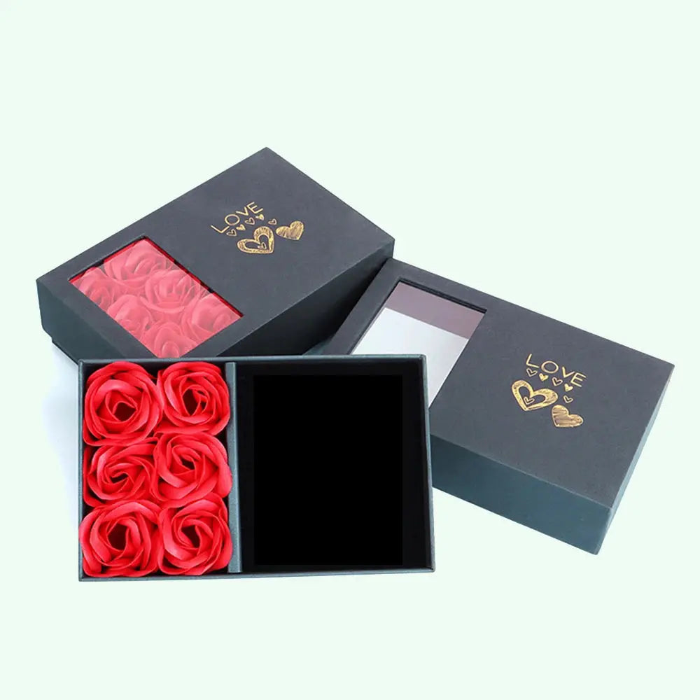 Jewelry box with six red rose petals, black exterior, window lid with gold love hearts design