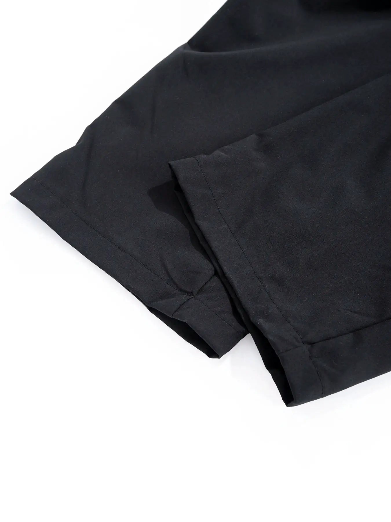 Men's black cargo pants with cuffed hems, closeup of fabric and seams