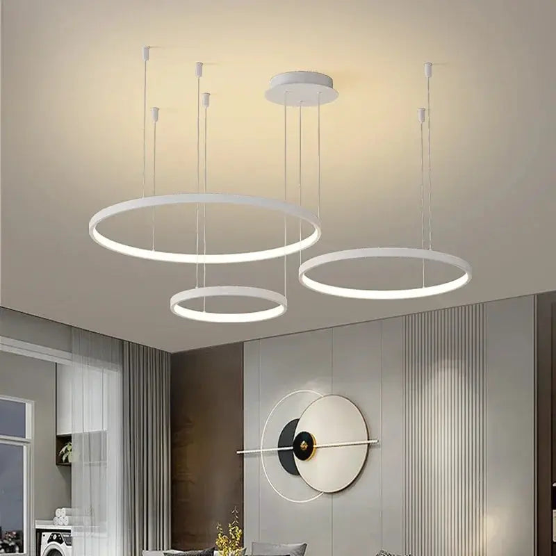 Three white circular LED ring pendant lights, modern acrylic chandelier style, ideal for living rooms