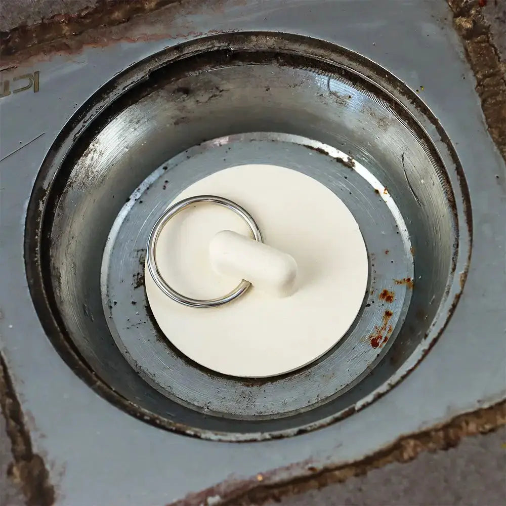 Sink drain stopper, white rubber plug with metal ring handle for bathroom or kitchen drains.