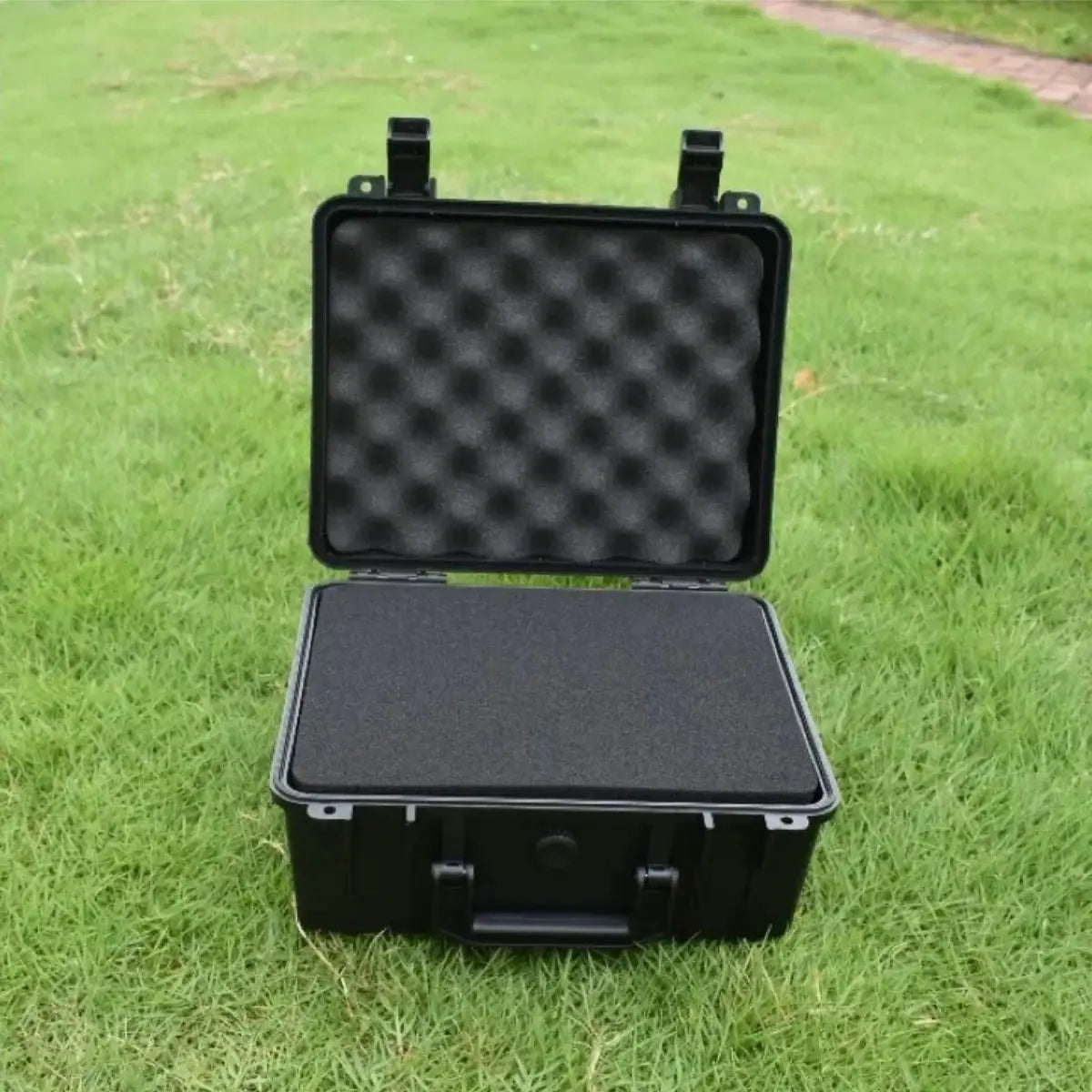Hard shell waterproof organizer box with foam-lined interior, black portable toolbox open on grass.