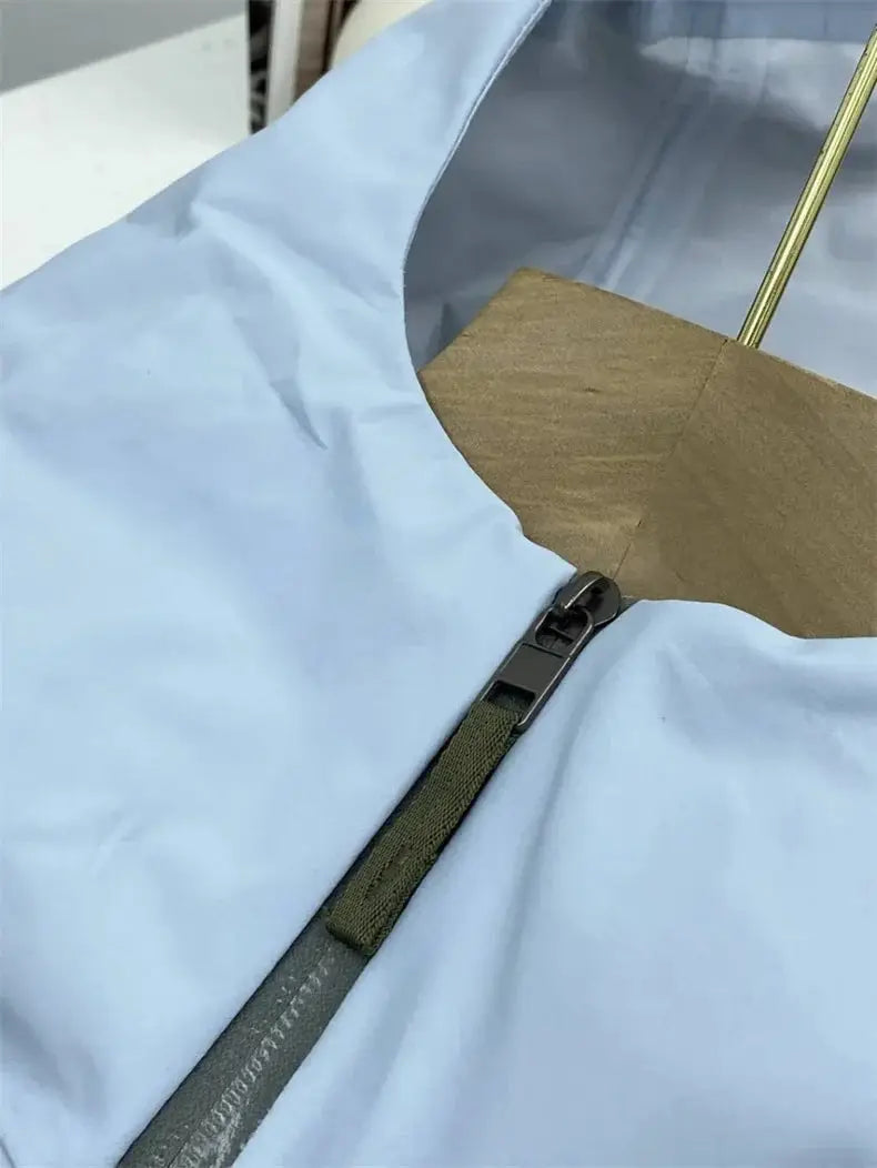 Men's light-blue windproof soft-shell jacket with front zipper and olive-green zipper tape.