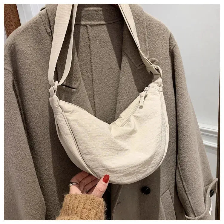 Nylon hobo crossbody bag for women in cream, crescent-shaped with a long adjustable strap.