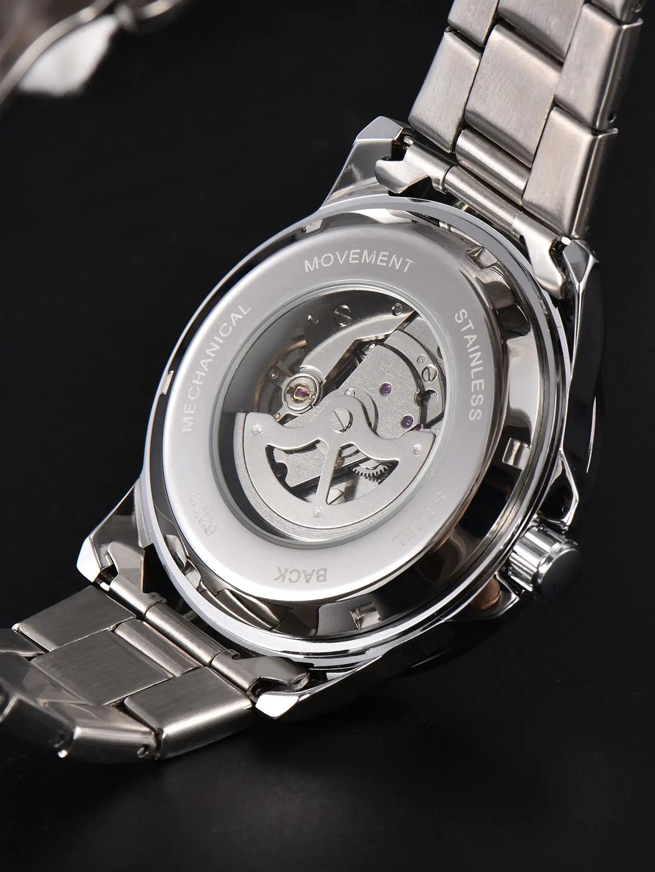 Men's stainless steel automatic watch with transparent case back showing movement and metal bracelet.