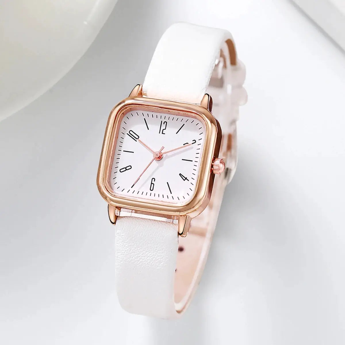 Women's square watch with white leather strap and rose-gold case.