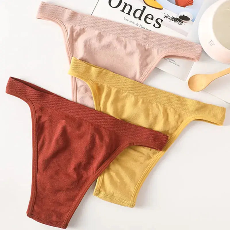 Three-piece ribbed low-rise thong underwear set in pink, mustard, and rust with breathable cotton gusset.