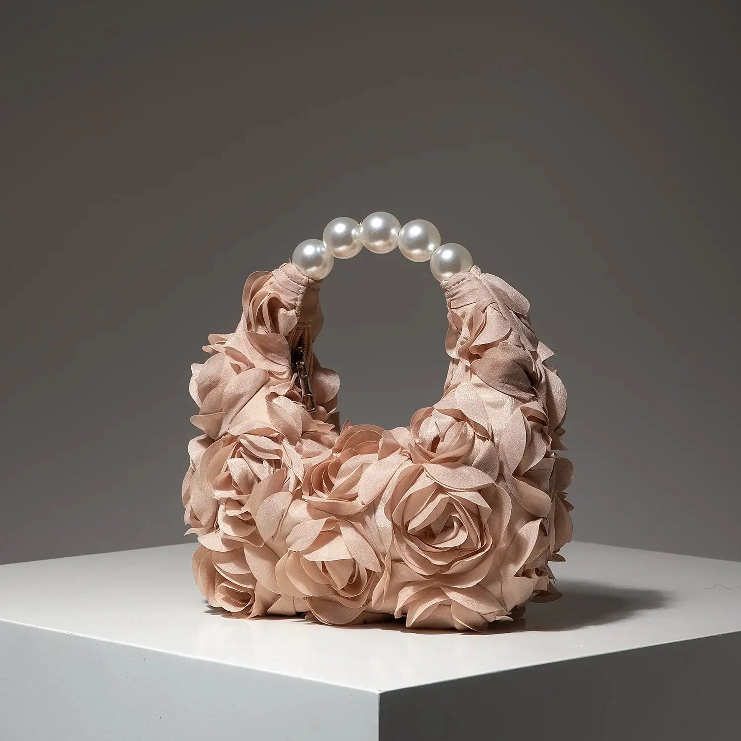 Pink floral handbag with pearl bead handle and ruffled petals, for gala occasions.