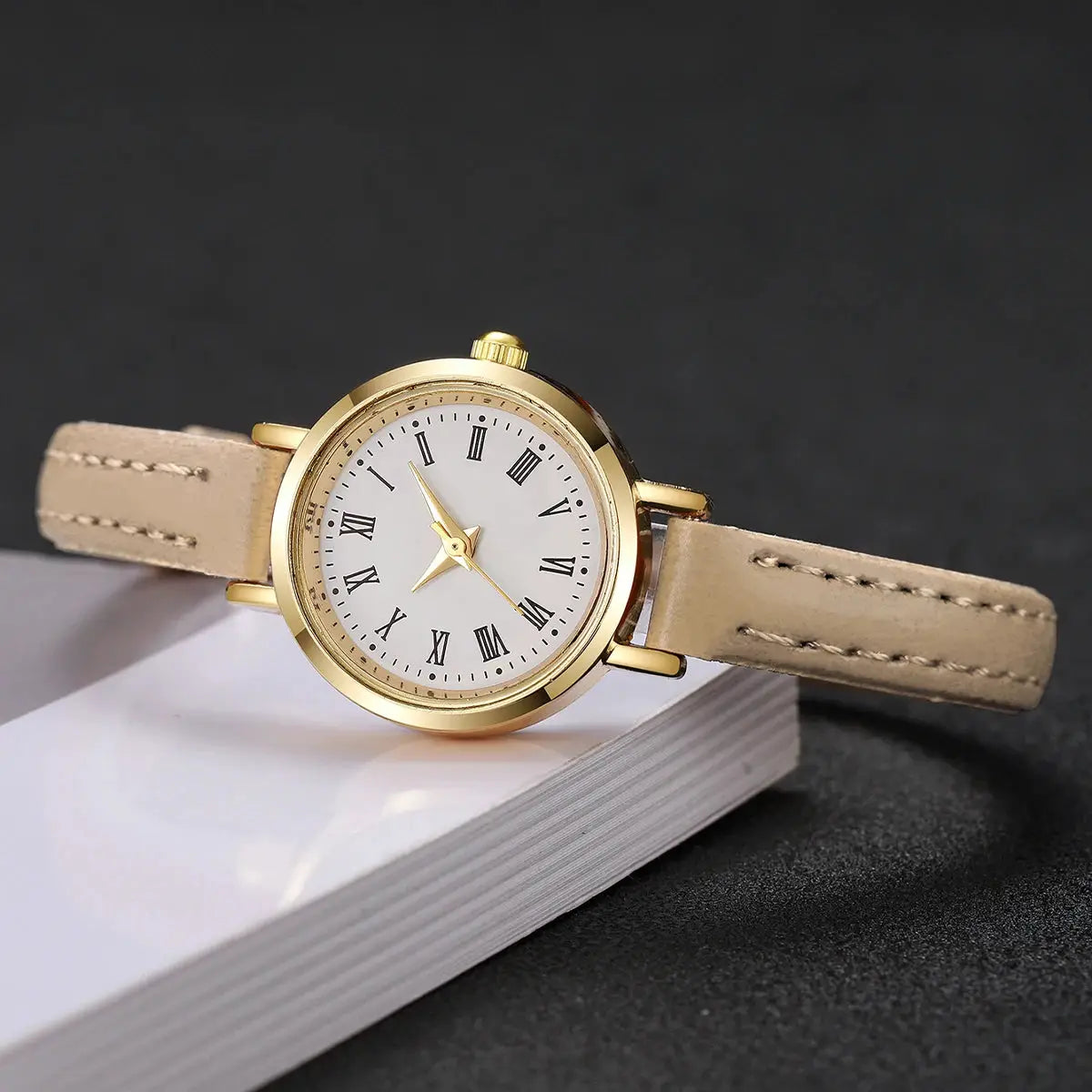 Women's gold-tone watch with beige leather strap, white dial and Roman numerals.