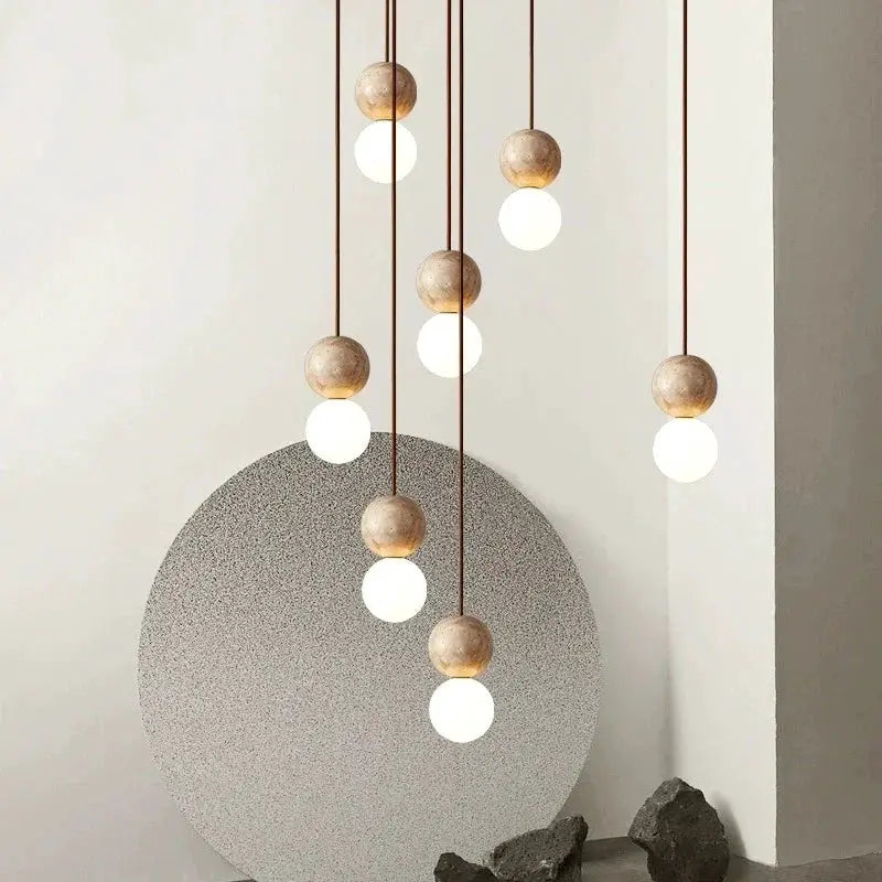 LED pendant light with cream stone beads, long hanging cords and round globe bulbs.