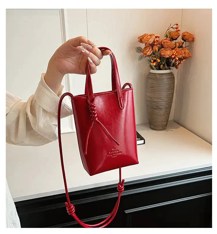 PU leather mini crossbody bag in red with knot-drawstring detail and long rope strap.