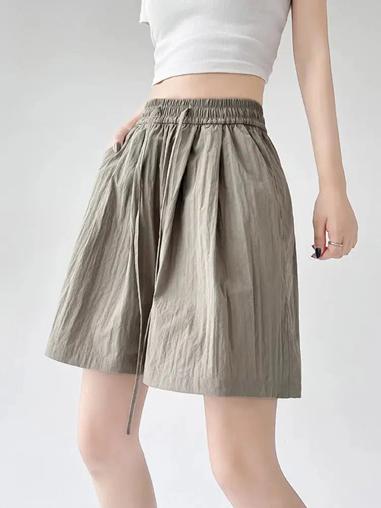 Summer women’s shorts by Simples Market: beige high-waisted elastic waistband, two pockets, loose knee-length shorts.