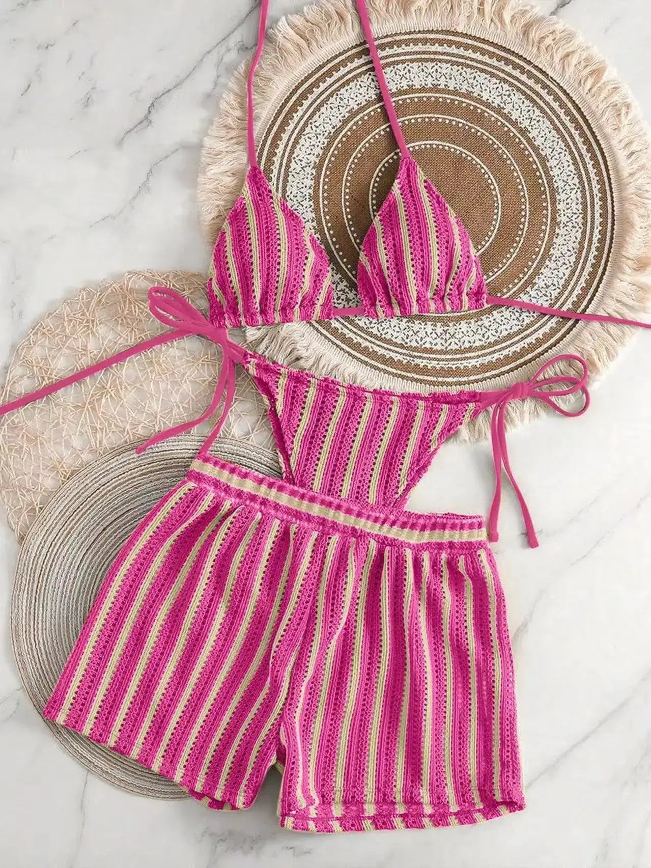 Pink striped three-piece women's bikini set with lace-up neck ties and side-tie bottoms on a woven mat