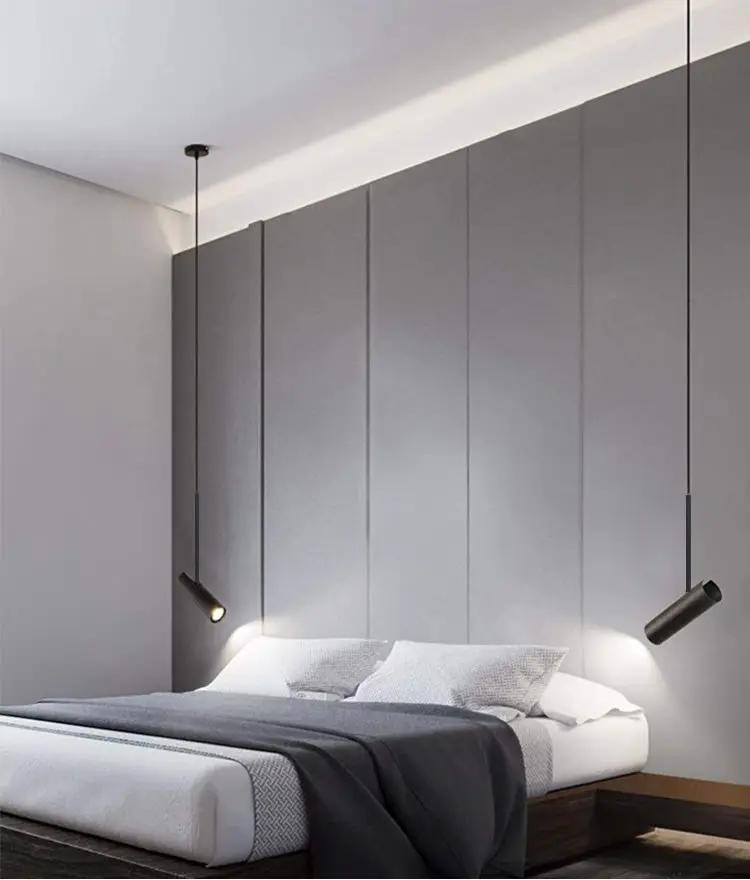 Minimalist black LED pendant lights (pair) hanging over a gray bed in a modern bedroom.