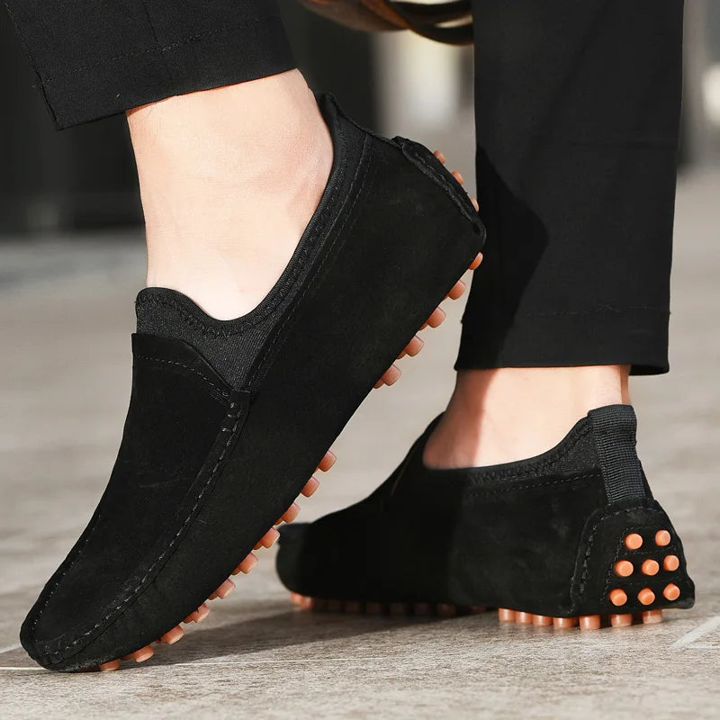 Men's black suede driving shoes with orange outsole studs, pair