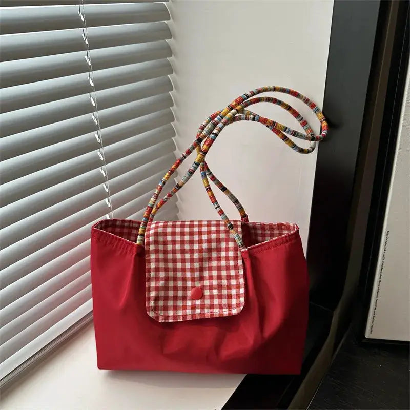 Red tote bag with gingham front pocket and multicolored braided handles