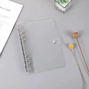Transparent plastic ring binder with snap strap and six rings for A5/A6 notebooks