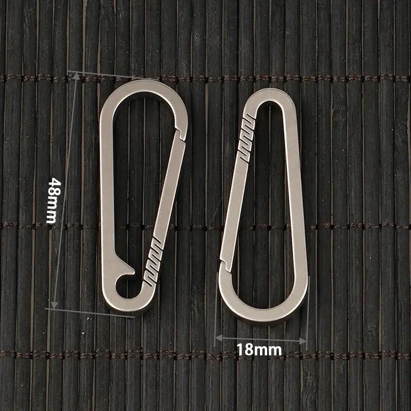 Two silver titanium alloy quick-release keychain carabiners, 48mm by 18mm, on dark background.