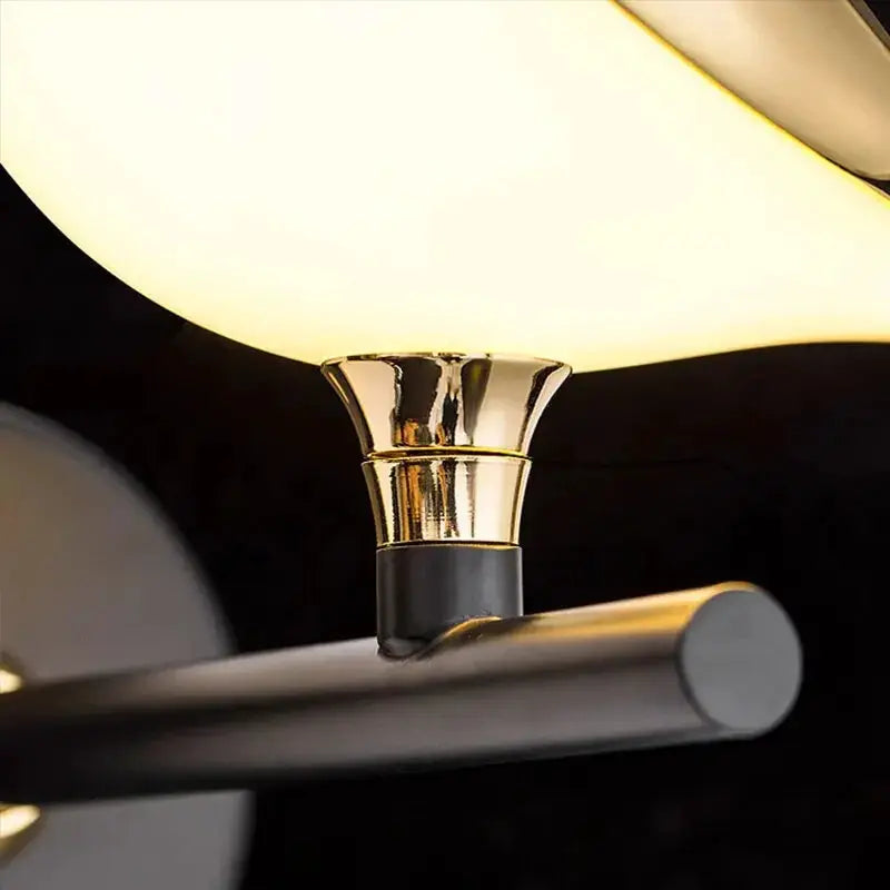 Modern LED wall lamp with gold-toned metallic fixture and black mounting, emits warm glow.