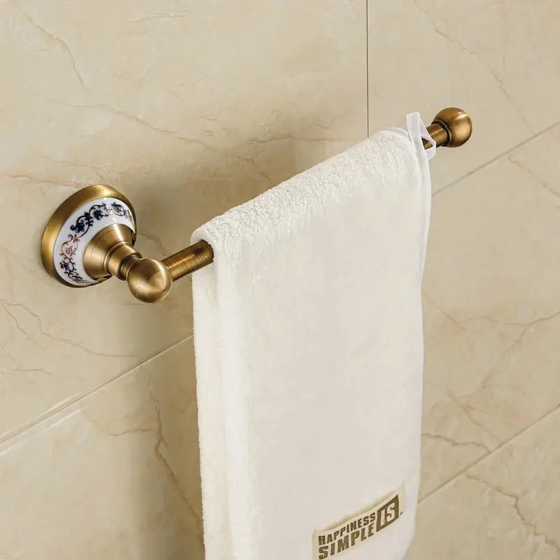 Antique brushed brass towel bar set with porcelain floral wall mounts and white towel