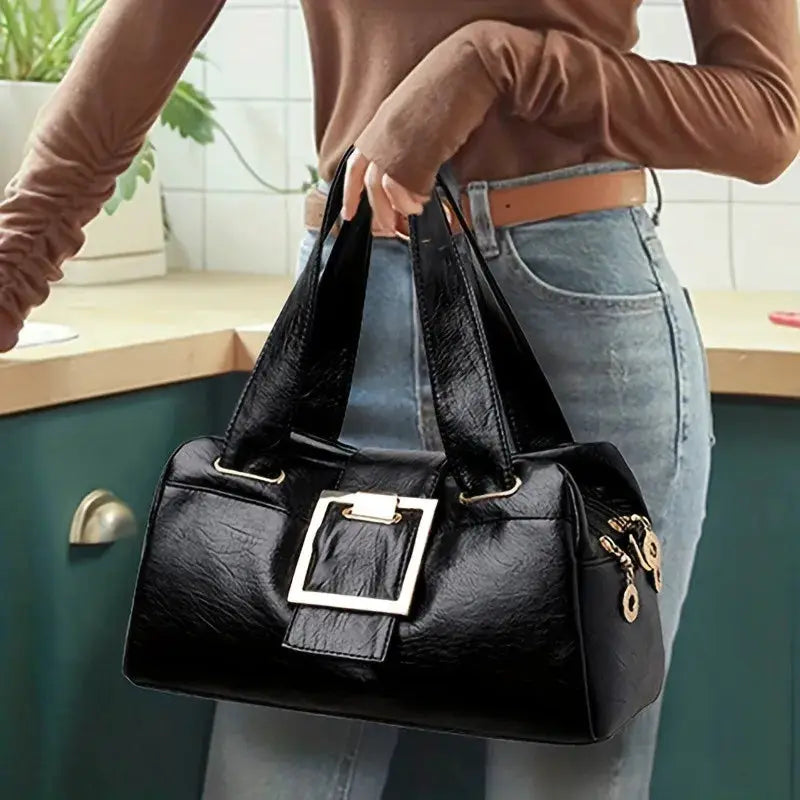 Women black leather top-handle bag with gold square buckle and roomy interior.
