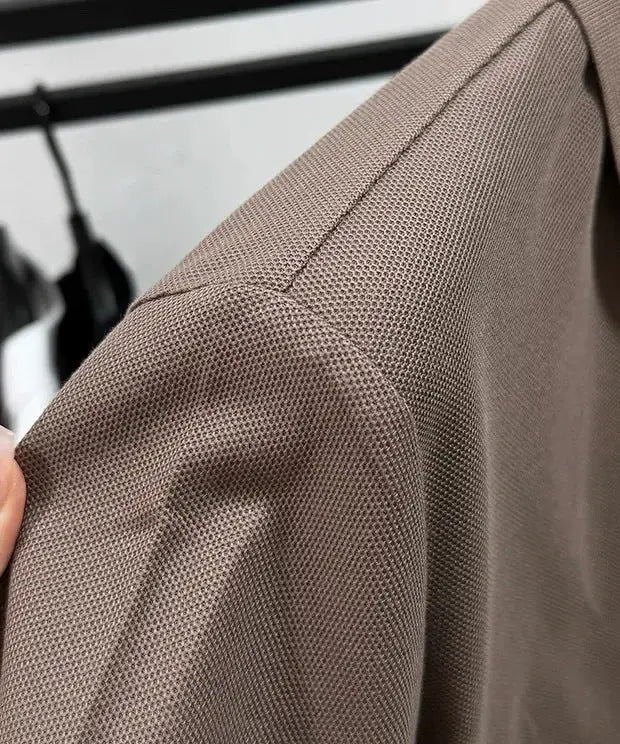 Polo shirt in taupe textured pique fabric, close-up of shoulder seam.