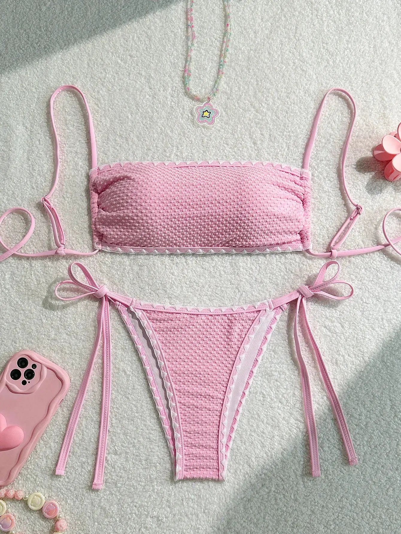 Pink dotted-texture two-piece bikini with bandeau top and side-tie bottoms.