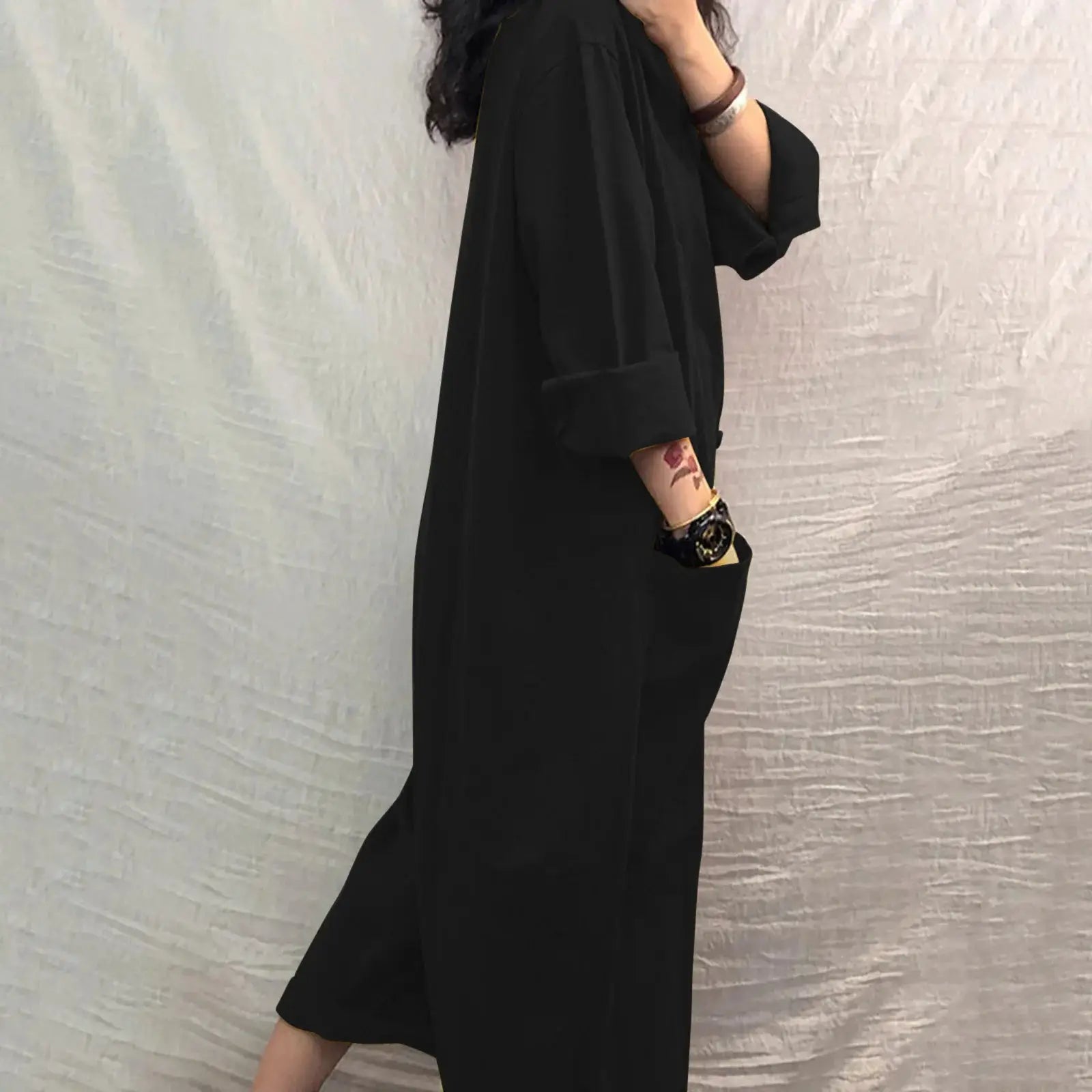 Black women's pocket jumpsuit, loose-fit with rolled sleeves and a side pocket.