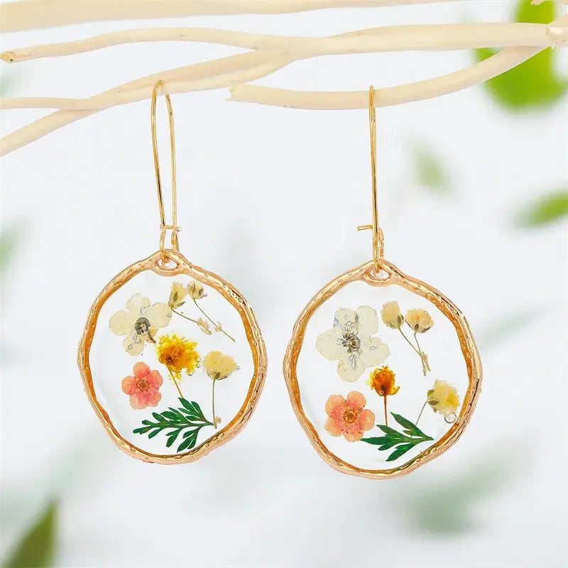 Pair of natural flower dangle earrings with colorful pressed flowers in epoxy resin and gold-tone frames.