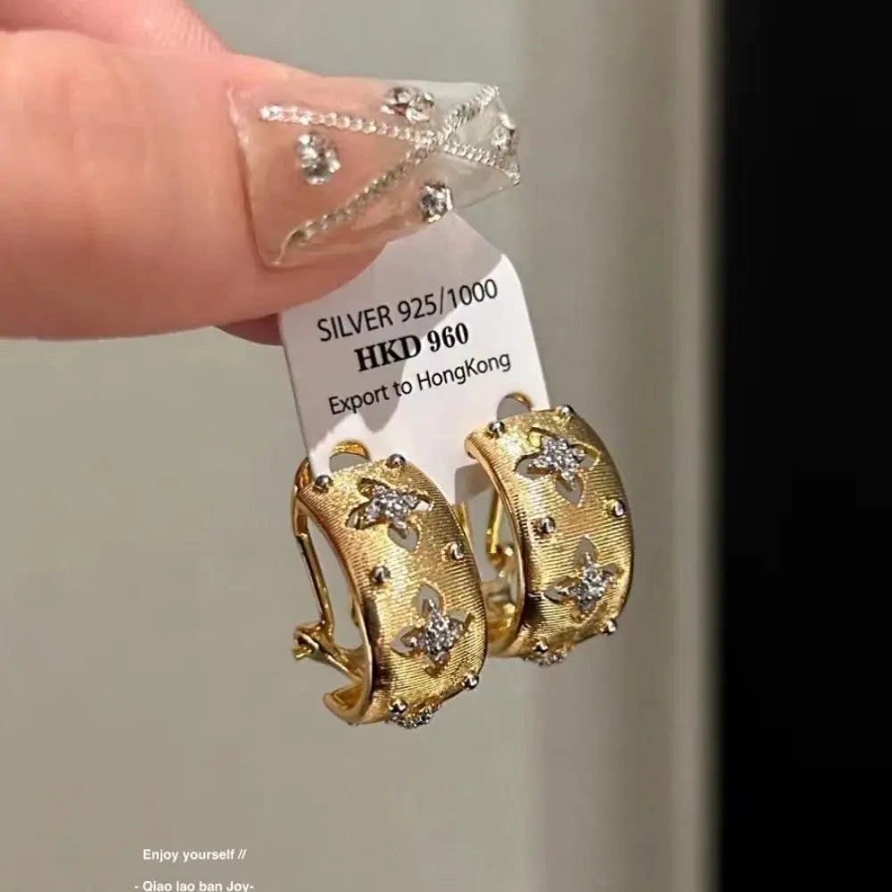 Gold-tone hollow flower hoop earrings with clear zircon crystals; pair