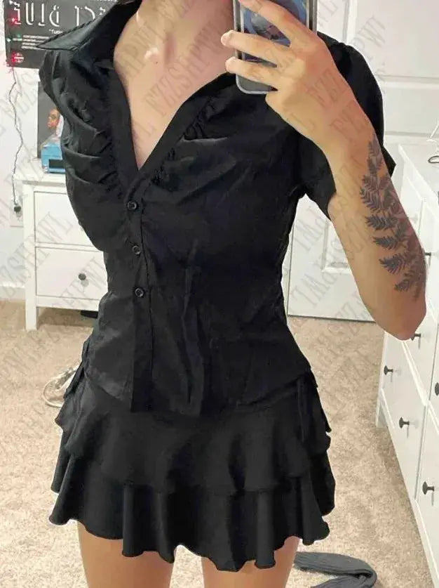 Black button-down blouse with ruffled short sleeves paired with a layered black mini skirt, two-piece outfit