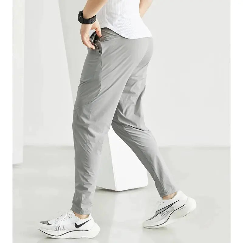 Men's gray running pants with pockets, paired with white Nike running shoes.