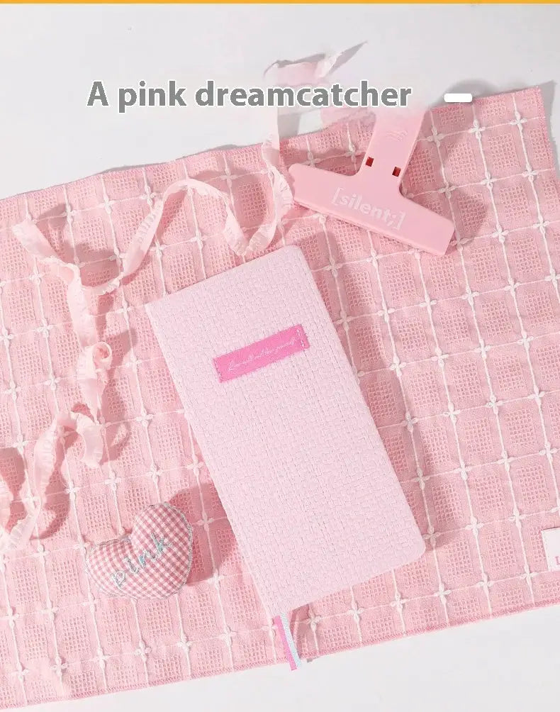 Pink weekly planner pocket notebook with textured cover on pink grid backdrop.
