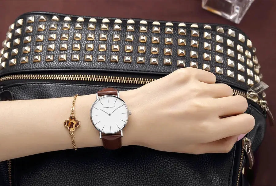 HANNAH MARTIN women’s wristwatch with brown leather strap and white dial; watch and gold bracelet shown