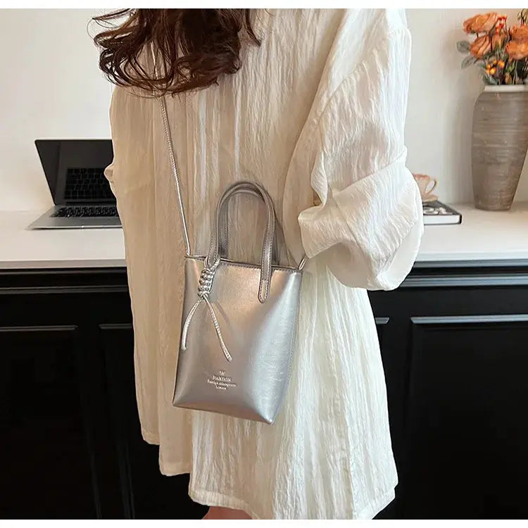 PU leather mini crossbody bag for women in metallic silver with top handles and an adjustable shoulder strap