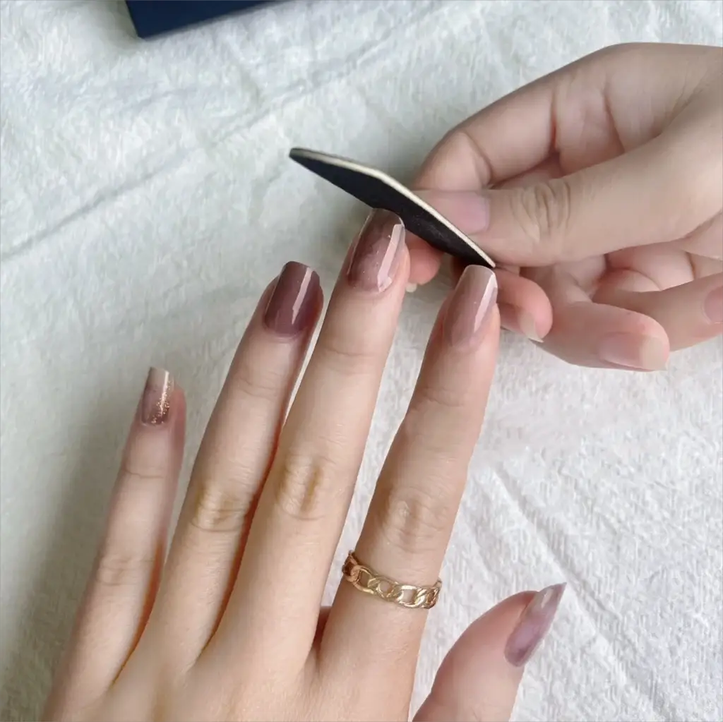 Gel nail wrap sheet held over nude gel nails; full-cover decal on black backing