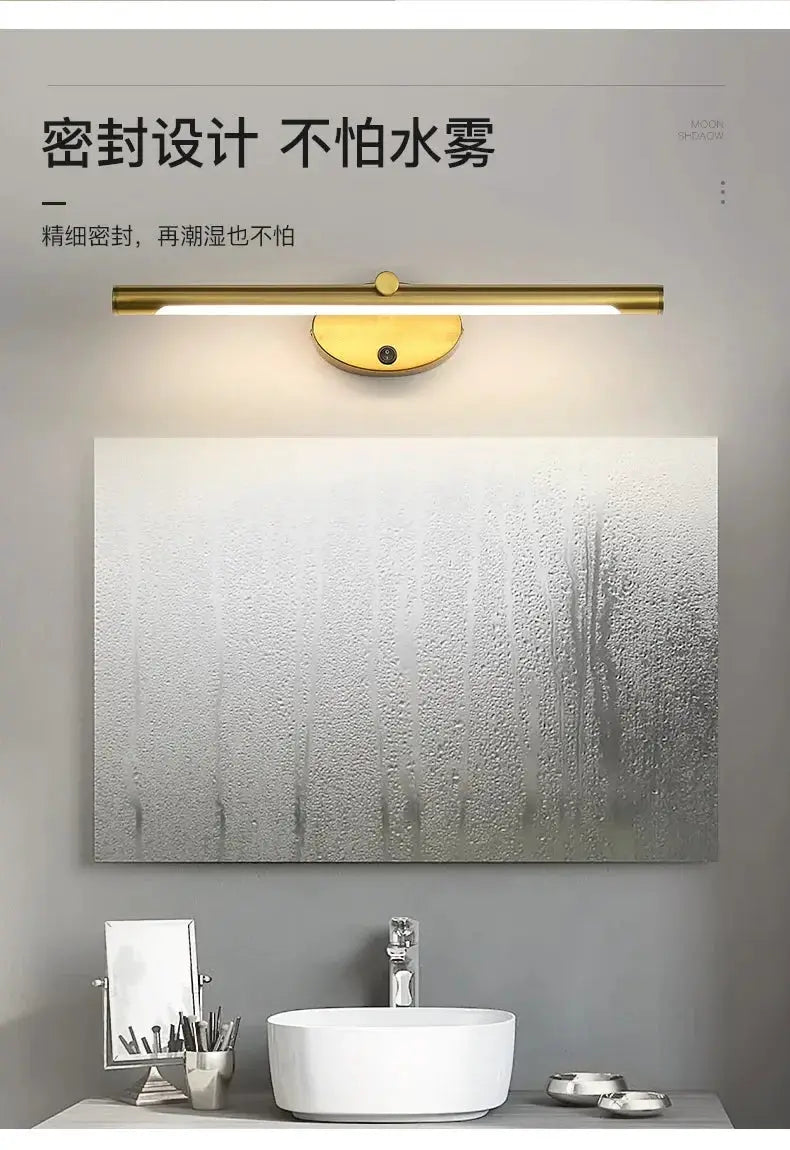Modern gold metal LED wall sconce with touch switch above bathroom mirror.