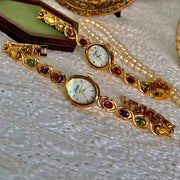2 gold-tone women's watches with round mother-of-pearl dials and colorful gemstone bezels