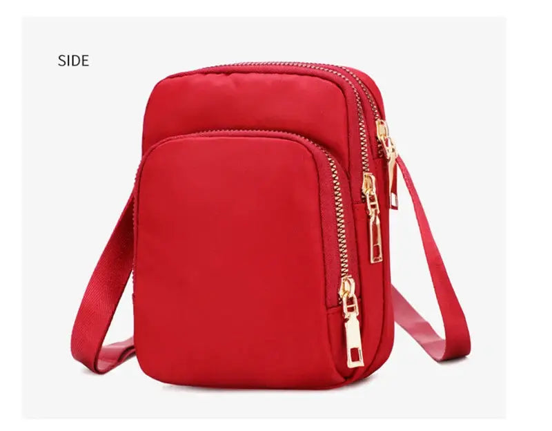 Women's red waterproof crossbody bag with front pocket and gold dual zippers.