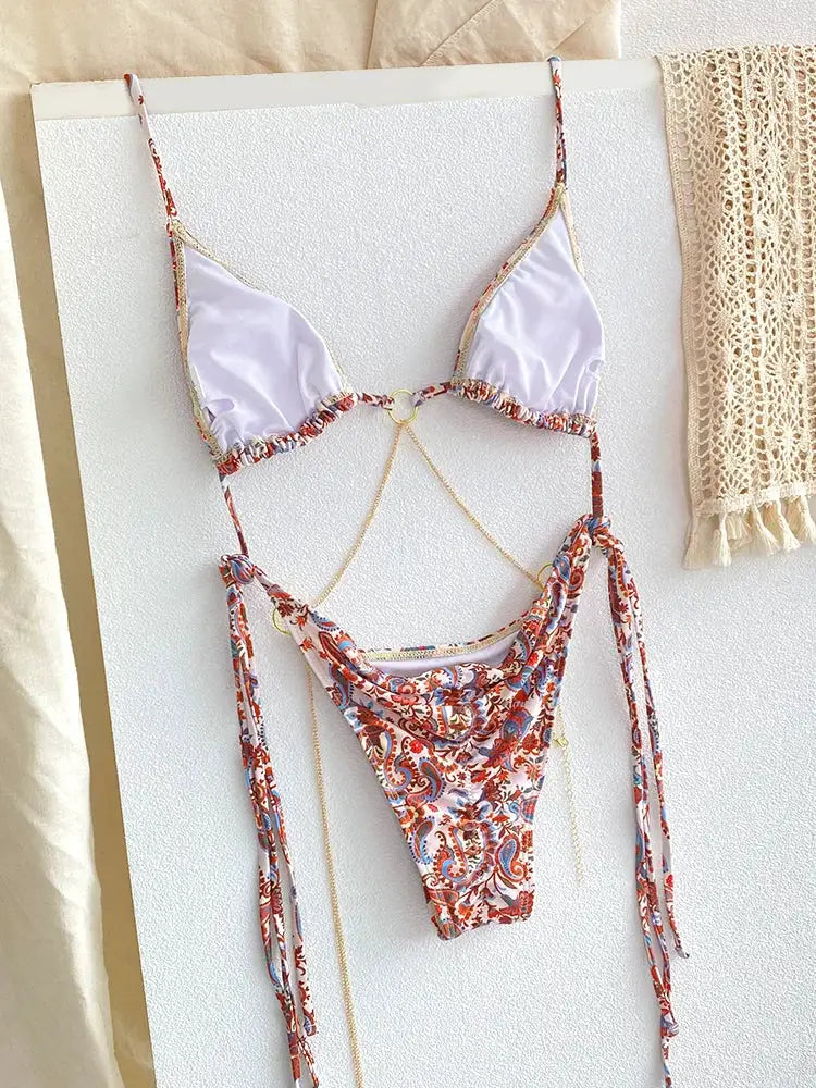 Bikini set by Simples Market: lavender triangle top with gold chain accents and paisley-print thong bottom