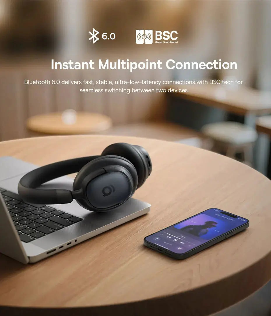 Baseus Bowie MH1 over-ear wireless headphones in black, resting on a laptop with a smartphone nearby