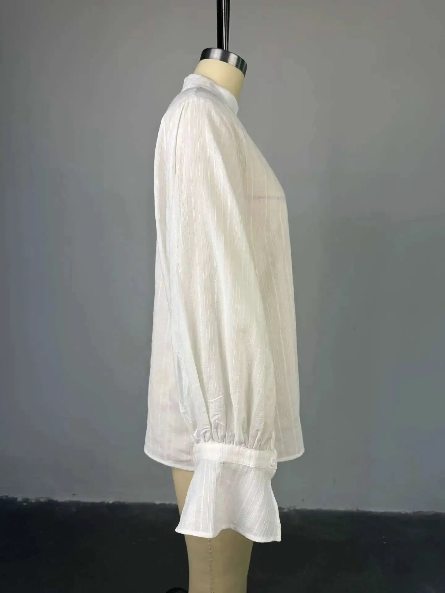 Oversized white cotton shirt with subtle vertical stripes, long sleeves, button-up