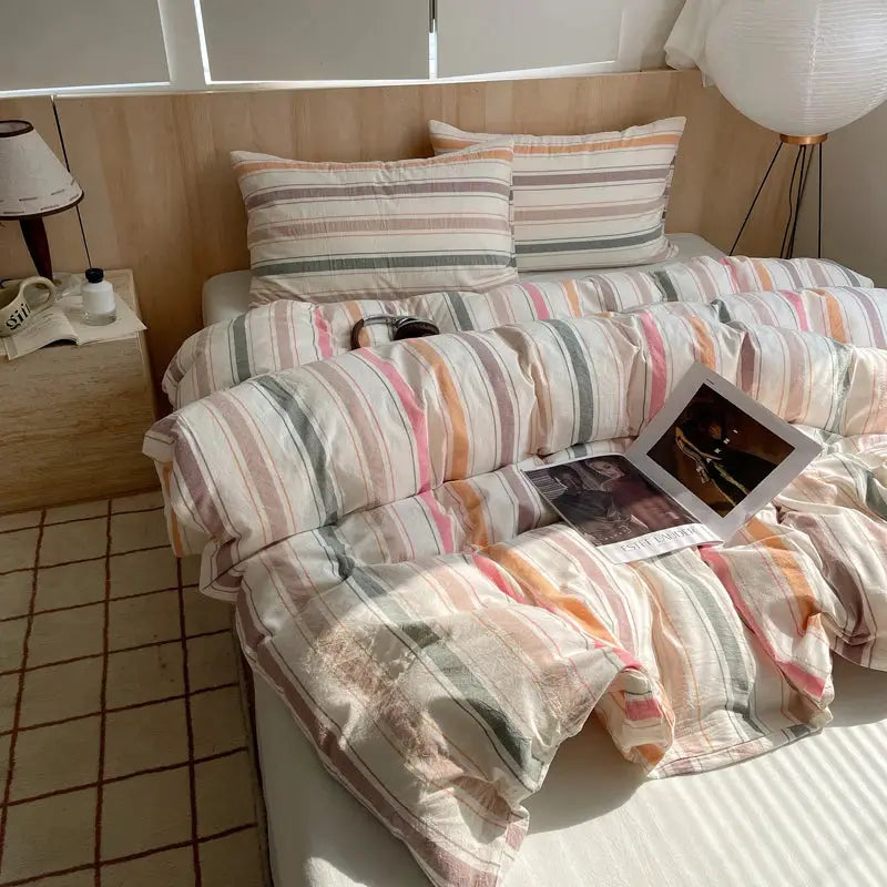 Cotton striped bedding set with duvet cover and pillowcases in pastel hues on bed
