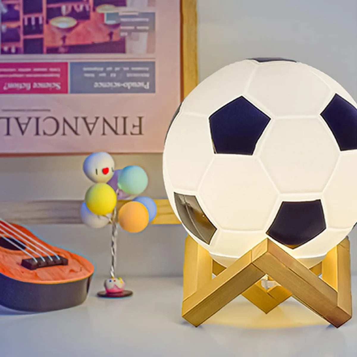 Soccer ball night light on a wooden X-shaped stand; 14 cm, white with dark panels, glowing desktop decoration.