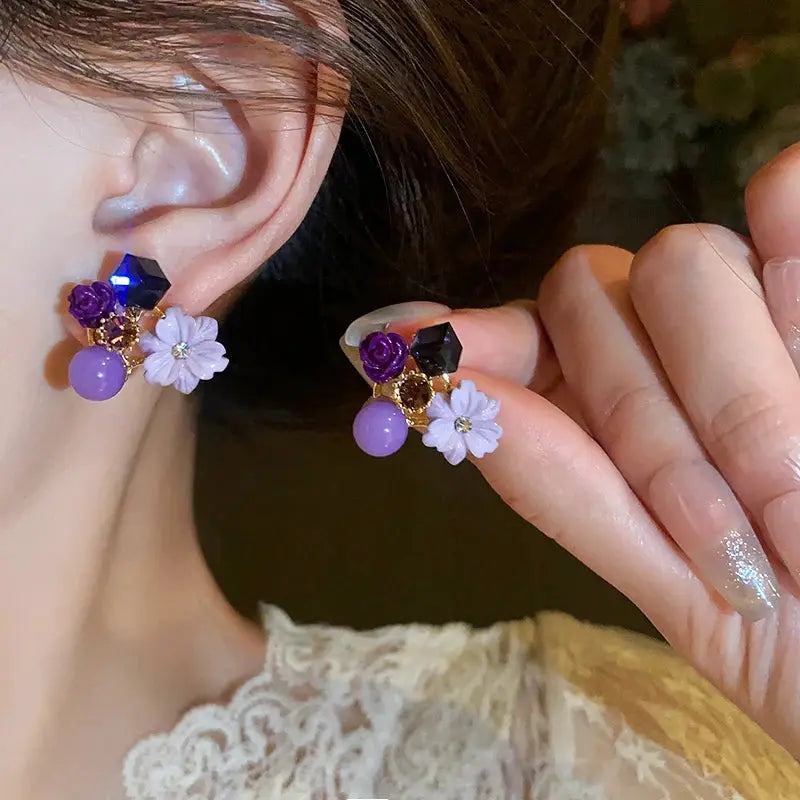 Pair of colorful flower earrings with purple beads, lilac daisies, and faceted black geometric accents