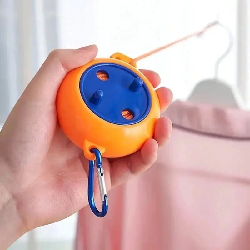 Portable retractable clothesline device, orange with blue dial, carabiner clip for travel laundry drying