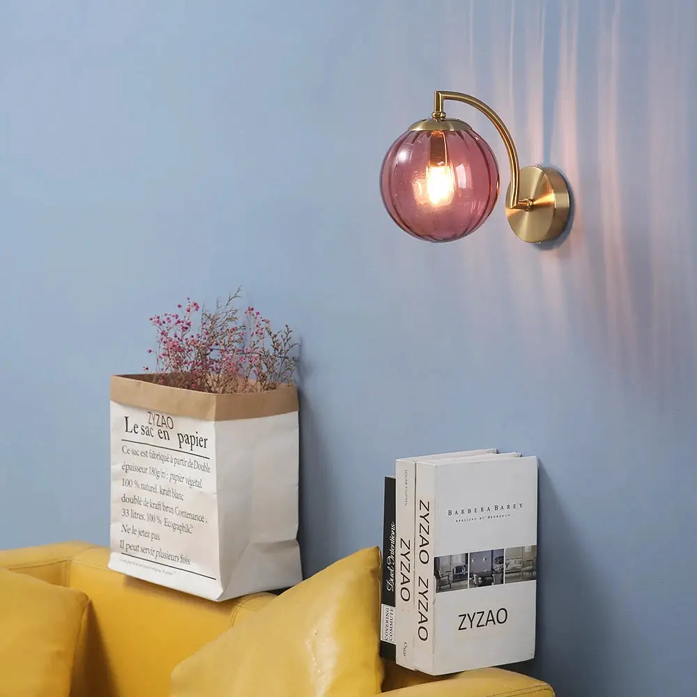 Simples Market modern LED wall lamp with pink glass shade and brass finish mounted on a blue wall.