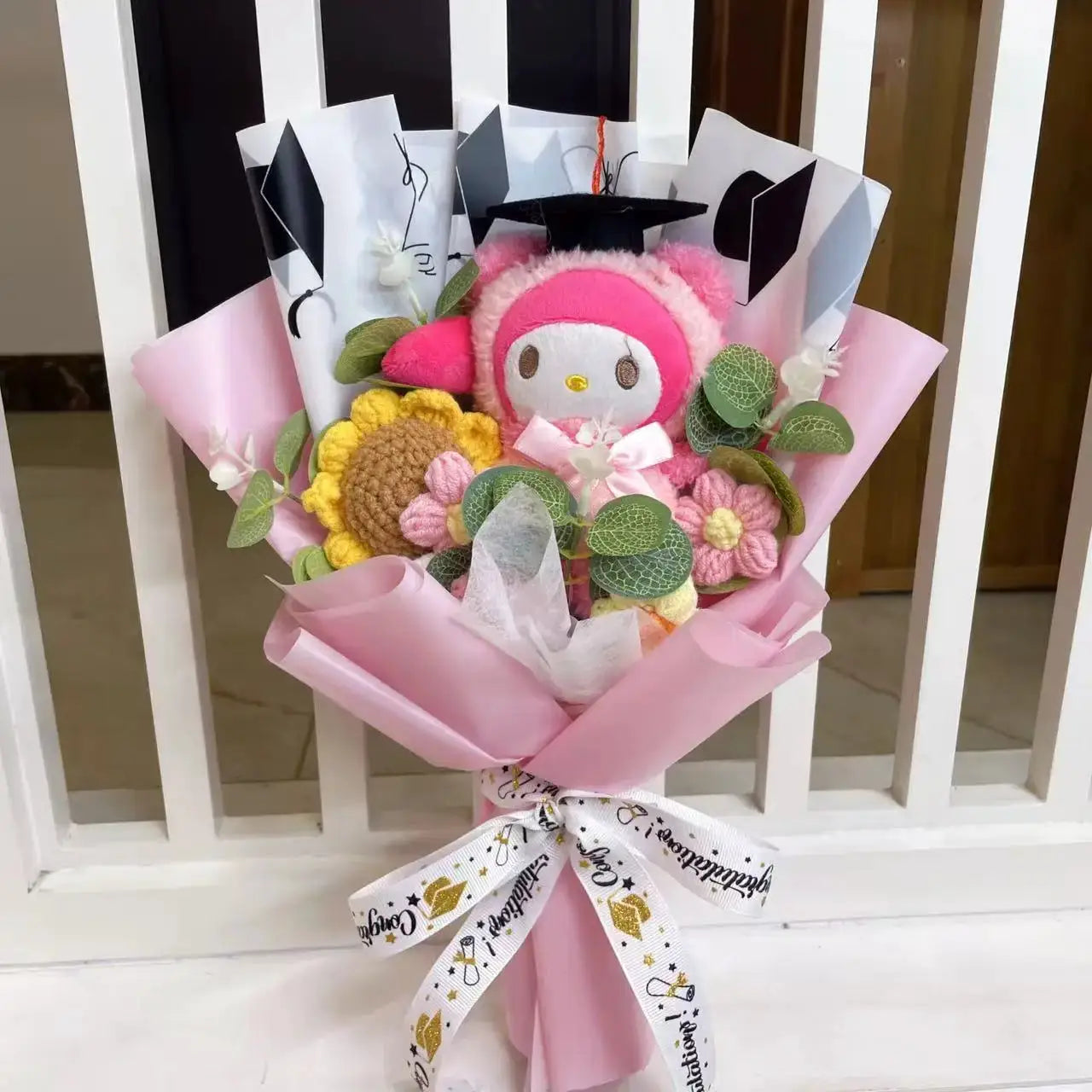 Stuffed plants bouquet by Simples Market; pink plush character with crochet flowers, pink wrapping and graduation cap.