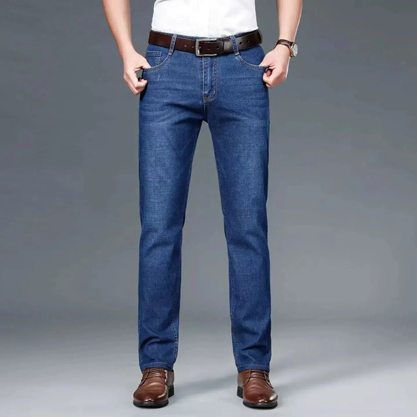 Men's blue denim jeans with straight-leg fit, brown belt and dress shoes